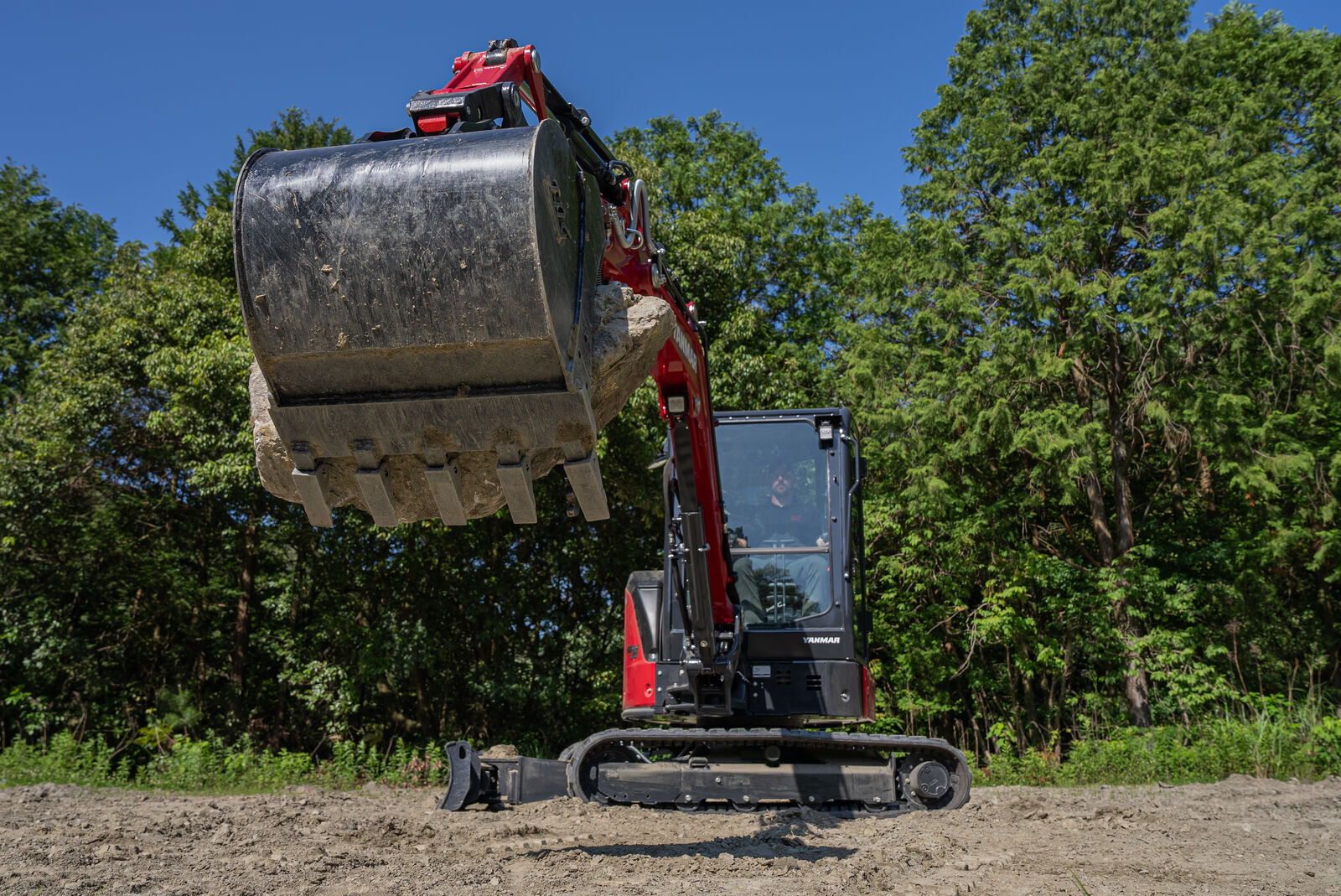 Yanmar ViO35-7 mini excavator holding a large rock in its bucket during heavy lifting operation.