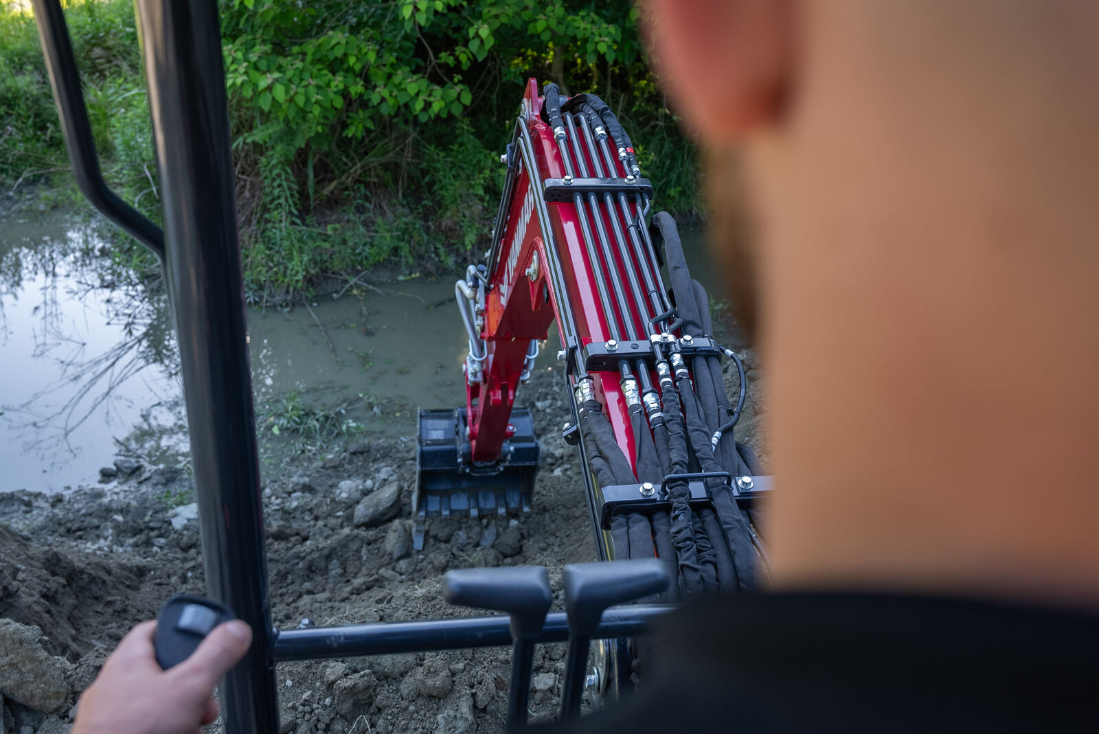 Over-the-shoulder view of operator using Yanmar ViO35-7 mini excavator to dig with precision.